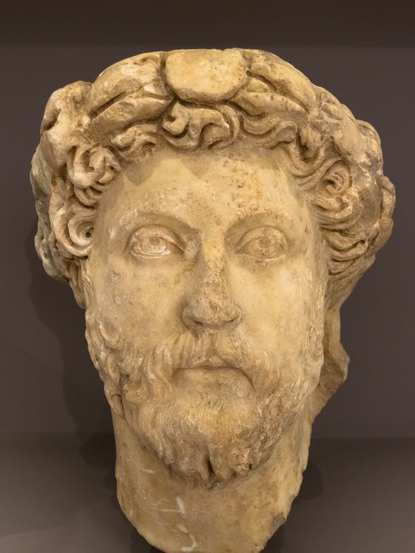 Buste de marbre de l'empereur Marc Aurèle, barbe bouclée, regard baissé.